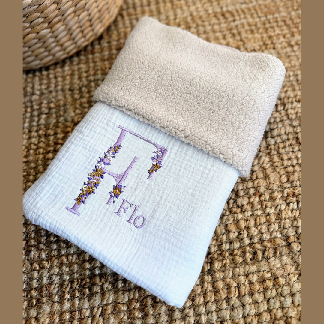 Opgevouwen babydeken met beige teddy aan de ene zijde en witte hydrofielstof aan de andere.