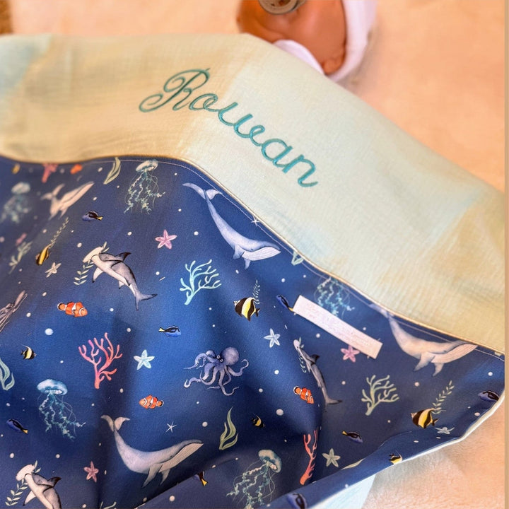 Babydeken met zeedierenprint, crèmekleurige voorkant en taupekleurige achterkant met naam.