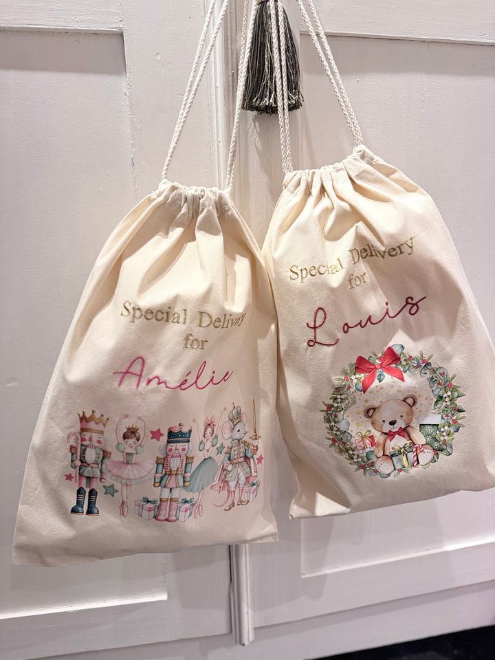 Twee beige kerstzakken met notenkrakerprint en beertjeprint, elk met de tekst Special Delivery en een geborduurde naam.