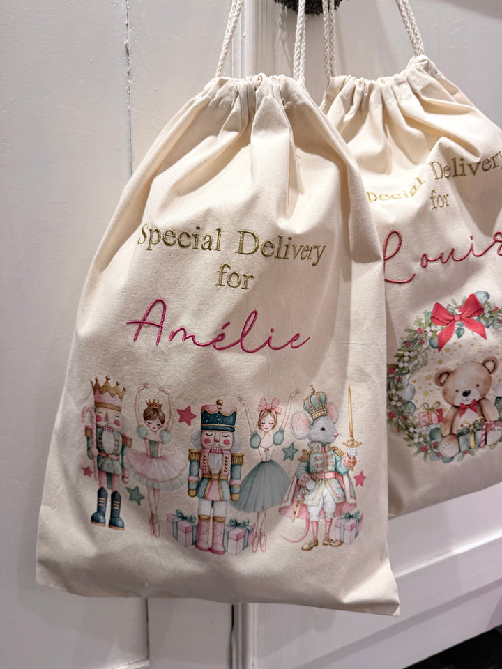 Close-up van de kerstzak met notenkrakerfiguren, ballerina’s en geborduurde naam onder de tekst Special Delivery.