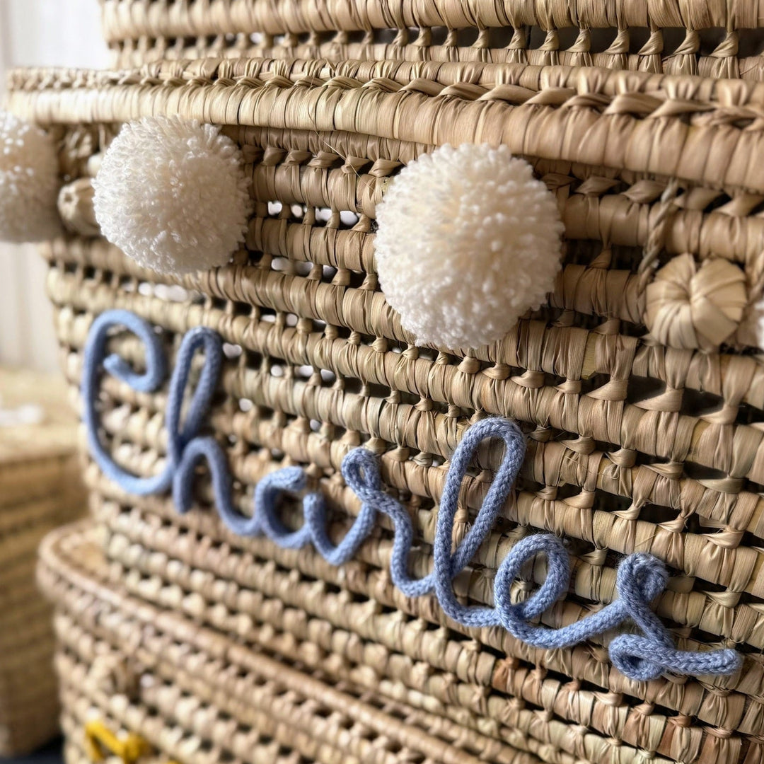Detail van een natuurlijke palmbladmand met grote blauwe punnikletters.