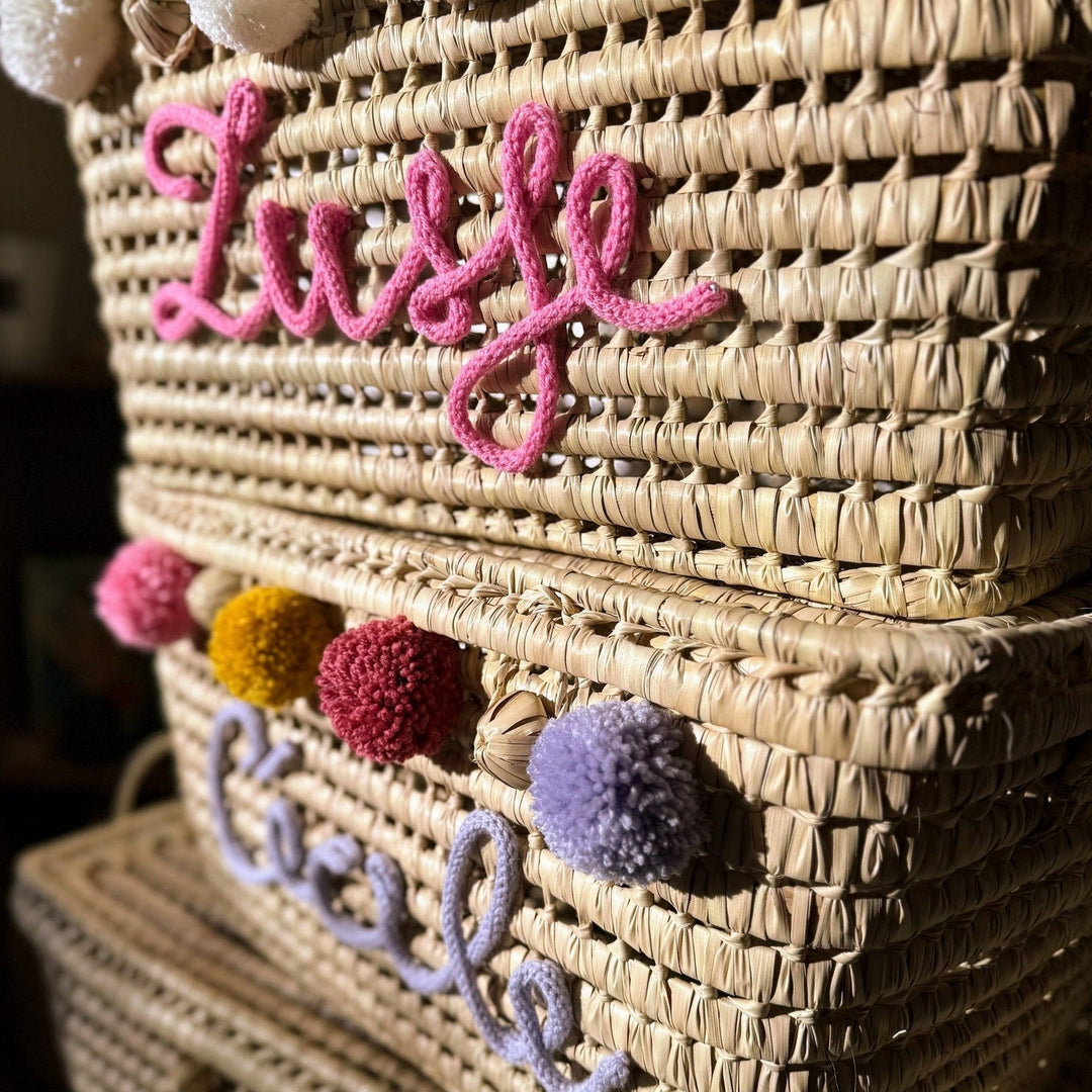 Close-up van roze punnikletters op een handgevlochten palmbladmand.