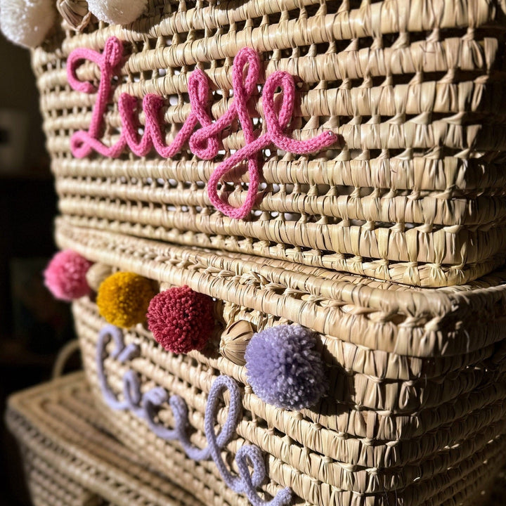 Close-up van roze punnikletters op een handgevlochten palmbladmand.